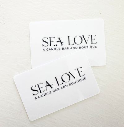 Two giftcard for 'sea love a candle bar and boutique' placed side by side on a plain white surface.