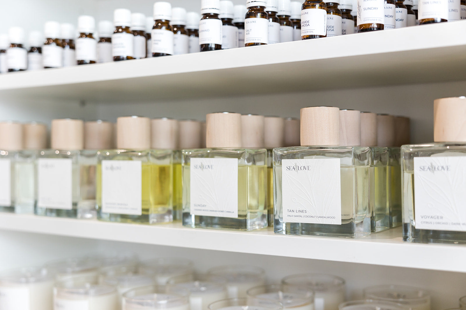 Elegant boutique shelf displaying a neat arrangement of luxury scented products, including candles and fragrances, with a minimalist aesthetic.